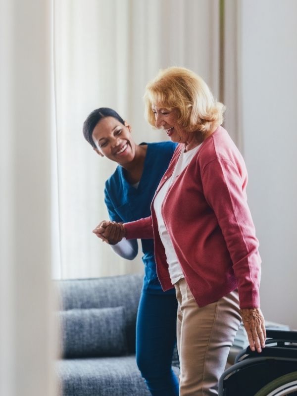 caregiver assisting elderly woman to get up