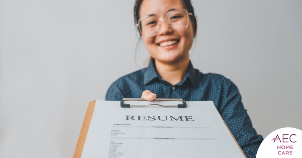 A woman happily hands in a resume, representing a successfully written caregiver resume.